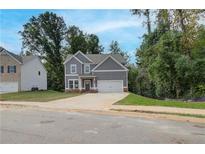 Two-story home featuring gray siding, white trim, an attached two-car garage, and a concrete driveway at 1097 Bodega Loop, Locust Grove, GA 30248