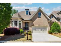 Charming brick home features a two-car garage, beautifully landscaped front yard, and dormer window at 95 Nesbit Reserve Ct, Alpharetta, GA 30022