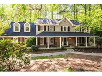Charming brick home featuring a covered front porch and dormer windows surrounded by lush greenery at 2685 Hearthstone Cir, Marietta, GA 30062