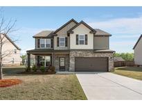 Charming two-story home with brick and siding, a well-manicured lawn, and an attached two-car garage at 336 Elaina Cir, Locust Grove, GA 30248