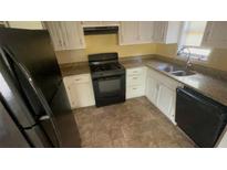Compact kitchen featuring white cabinets, laminate countertops, and black appliances at 100 Waters Edge Dr, Locust Grove, GA 30248