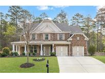 Charming brick home featuring a two-car garage, well-manicured lawn, and inviting front porch at 1964 Crosswaters Dr, Dacula, GA 30019