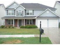 Charming two-story home with gray siding, a brick-accented porch, manicured lawn and a two-car garage at 2896 Spence Ct, Dacula, GA 30019