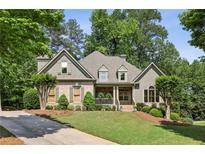 Charming brick home with a well-manicured lawn, mature trees, and a welcoming front porch at 9075 Preston Ln, Suwanee, GA 30024