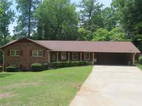 Charming brick home with well-maintained lawn, and carport, nestled amongst mature trees at 4141 Fredericksburg Dr, College Park, GA 30337