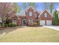 Charming two-story brick home featuring a well-manicured lawn, blooming flowers, and a two-car garage at 625 Park Creek Trce, Alpharetta, GA 30005