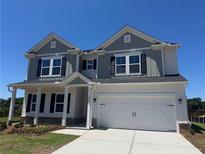 Charming two-story home with a two-car garage, covered porch and gray wood facade under a bright blue sky at 1636 Tide Mill Rd, Cumming, GA 30040