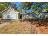 Charming single-story home with attached garage, manicured lawn, and mature trees at 6520 Emerald Pointe Cir, Atlanta, GA 30349