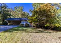 A single story home with brick accents, mature trees, carport, and a well-manicured front yard at 8596 Timberlane Dr, Douglasville, GA 30134