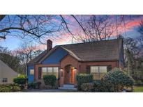 Charming brick home featuring an arched doorway and complemented by manicured landscaping at twilight at 958 Winburn Dr, Atlanta, GA 30344