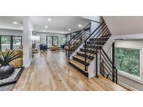 Bright foyer boasts hardwood floors, staircase with black metal railings, and view to living room with backyard access at 120 Huntcliff Pt, Atlanta, GA 30350