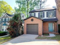 Charming two-story townhome with a brick facade, grey shutters, an attached garage, and a light blue front door at 1379 Vintage Pointe Dr, Lawrenceville, GA 30044