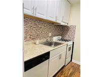 This kitchen features a gas range, tile backsplash and white cabinets at 2805 Ne Ne Expressway Ne # B-26, Atlanta, GA 30345