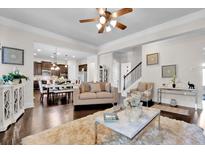 Bright living room featuring hardwood floors, a ceiling fan, and a seamless flow into the kitchen at 15 Granville Ln, Covington, GA 30016