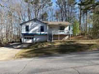 Split-level home with a front-facing garage, a covered front porch, and a yard at 506 Carlton Dr, Palmetto, GA 30268