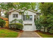 Charming white brick home with a well-manicured front yard, driveway, and attached one-car garage at 648 Channing Nw Dr, Atlanta, GA 30318