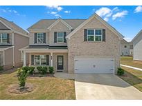 Charming two-story home with a light brick exterior, attached garage, and beautifully manicured landscaping at 70 Clark Lake Ln, Grayson, GA 30017
