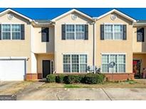 Attractive townhome featuring a two-car garage, well-maintained landscaping, and traditional architectural details at 2384 Coach Way, Jonesboro, GA 30236