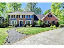 Charming brick home featuring a well-manicured lawn, mature trees, and a welcoming front entrance at 5023 Buckline Xing, Dunwoody, GA 30338