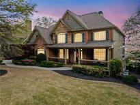 Stunning two-story home boasts a brick and stone facade, covered porch and lush landscaping at 322 Tupelo Tr Trl, Canton, GA 30114