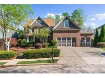 Beautiful brick home with a three car garage, mature landscaping, and manicured lawn at 4620 Westgate Dr, Cumming, GA 30040