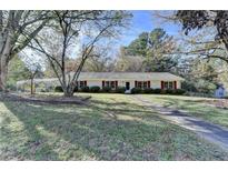 Charming ranch home with mature trees, red shutters, and lush lawn at 3081 Frankie Ln, Duluth, GA 30096