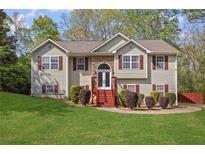 Charming two-story home with a well-manicured lawn and a welcoming front entrance with stone accents and red shutters at 6332 Fairoaks Pl, Douglasville, GA 30135