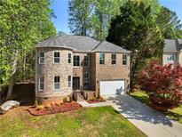 Charming two-story brick home with a turret-style stone accent and well-manicured lawn at 6960 Dockbridge Way, Stone Mountain, GA 30087