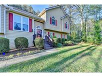 Charming two-story home with red shutters, a lush lawn, and mature landscaping offering great curb appeal at 6040 Carriage Dr, Cumming, GA 30028