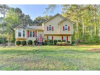 Charming home featuring a manicured lawn, classic architectural details, and bright red window shutters at 6040 Carriage Dr, Cumming, GA 30028