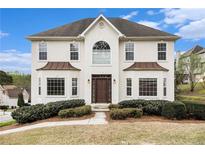 Stucco two-story home with manicured landscaping and a dark roof under a blue sky at 6028 Connaught Se Dr, Mableton, GA 30126