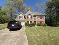Charming two-story brick home featuring a well-manicured lawn and attached two-car garage at 449 Tara Oaks Trl, Lawrenceville, GA 30043