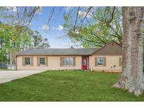 Charming single-story home featuring a well-maintained lawn and a welcoming red front door at 140 Apple Valley Dr, Woodstock, GA 30188