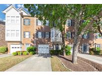 Brick townhome with black shutters, a single car garage and mature landscaping at 2180 Mill Garden Run, Buford, GA 30519