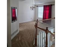 View of living room with red curtains, staircase, chandelier and neutral-colored carpet at 204 Millpond Pkwy, Villa Rica, GA 30180
