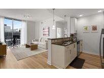 Bright living room with a modern kitchen, a comfortable sofa, and a large window with city views at 855 Peachtree Ne St # 2706, Atlanta, GA 30308