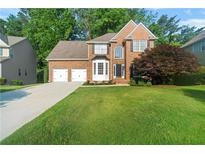 Charming two-story brick home featuring a well-manicured lawn, two-car garage, and mature trees at 155 Glenside Ln, Duluth, GA 30097