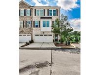 Charming brick townhome with a two-car garage, complemented by manicured landscaping and beautiful architectural details at 125 Sidney St, Marietta, GA 30060