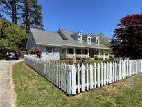 Charming home featuring a white picket fence, manicured lawn, and covered porch at 5167 Manitu Sw Ct, Lilburn, GA 30047