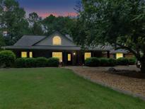 Charming single-story home with manicured lawn, mature trees, and inviting front porch at twilight at 219 Riverbrook Ct, Mcdonough, GA 30252