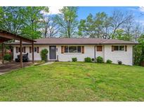 Charming brick home featuring well-maintained lawn, shutters and a covered carport at 605 Rocky Branch Rd, Villa Rica, GA 30180