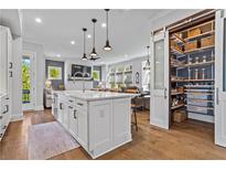 Bright kitchen features a large island with a white countertop and a walk-in pantry with sliding doors at 7515 Cordery Rd, Cumming, GA 30040