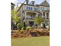 Charming townhouse featuring a front porch, balcony, and manicured lawn with a bench at 1129 Cordia Nw Ave, Atlanta, GA 30318