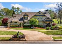 Charming two-story home with landscaped yard, circular driveway, and classic architectural details at 3018 Bradshaw Club Dr, Woodstock, GA 30188