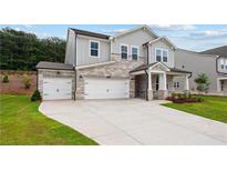 Charming two-story home with stone accents, a three-car garage and well-manicured front lawn at 719 Crossroad Ct, Powder Springs, GA 30127