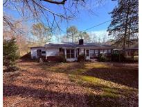 Charming ranch-style home with a welcoming porch, nestled on a wooded lot with mature trees at 214 S Lake Dr, Hiram, GA 30141