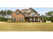 Two-story brick and siding home with a well-manicured lawn and covered front porch at 209 Brynn Ln, Mcdonough, GA 30252