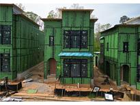New construction exterior view showing modern design with black window frames and green sheathing at 11863 Serenbe Ln, Chattahoochee Hills, GA 30268