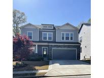 Charming two-story home with gray siding, stone accents, a two-car garage, and a well-maintained front yard at 5990 Arbor Green Cir, Sugar Hill, GA 30518