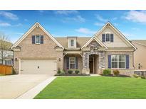 Charming brick home with a manicured lawn, attached garage and stone accents at 403 Aristides Way, Canton, GA 30115